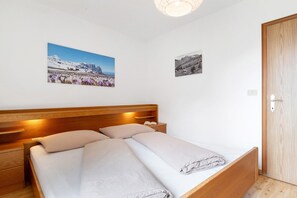 Une chambre à coucher avec un lit en bois, deux tables de chevet et deux tableaux accrochés au mur.