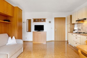 Une cuisine moderne avec des meubles en bois, un téléviseur encastré et un parquet disposé en motif chevron.