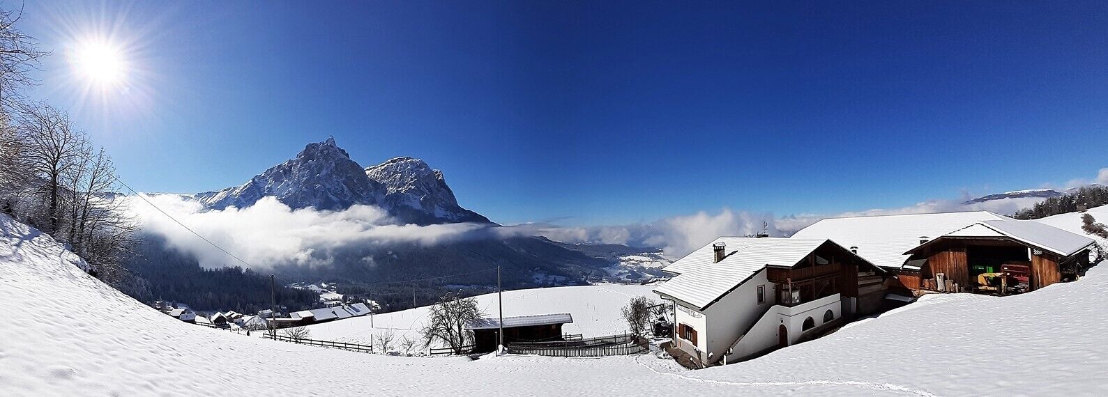 A snow-covered mountain village with wooden buildings and a prominent peak in the background.