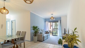 A modern living room with a sofa, a dining table with chairs, and a large window with curtains. - Apt With Barbecue in Lagoa da Conceicao Sro0002 (Florianópolis)