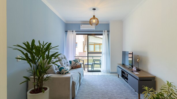 A modern living room with a sofa, a coffee table, a TV, and a potted plant. - Apt With Barbecue in Lagoa da Conceicao Sro0002 (Florianópolis)