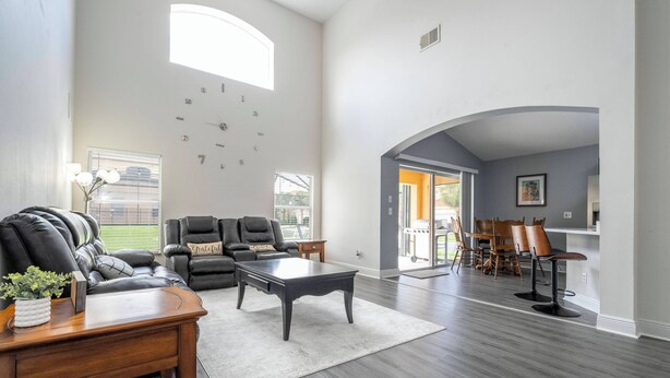 A spacious living room with a leather sofa, a coffee table, and a dining area with chairs and a table. - Gorgeous and Confort 4 bedrooms (Davenport)