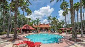 A swimming pool with lounge chairs, palm trees, and a building with a red roof. - Gorgeous and Confort 4 bedrooms (Davenport)