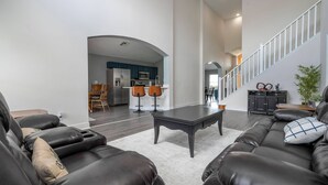 A spacious living room with a dark leather sofa, a coffee table, and a staircase leading to an upper level. - Gorgeous and Confort 4 bedrooms (Davenport)