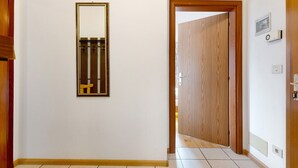 Un pasillo con una puerta de madera, un espejo y un termostato en la pared.