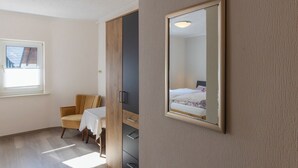 A bedroom with a bed, a chair, a table, and a wardrobe. - Vacation apartment Am Park (Schmallenberg)