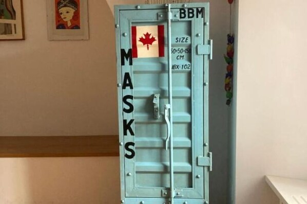 A blue metal door with the word "MASKS" on it, a Canadian flag, and size information.