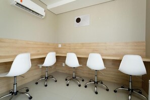 A conference room with four white office chairs, a wooden panel wall, and an air conditioning unit. - SPA - Amazing Studios in Floripa-sc (Florianópolis)