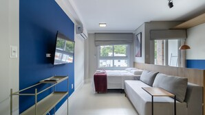 Ett modernt rum med en soffa, en tv som är monterad på väggen, ett fönster med utsikt och ett litet bord.