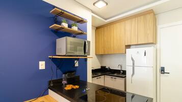 A modern kitchen with a black countertop, a built-in microwave, a stove, and wooden cabinets.
