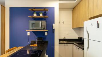 A modern kitchen with a blue accent wall, wooden cabinets, a white refrigerator, and a built-in microwave.