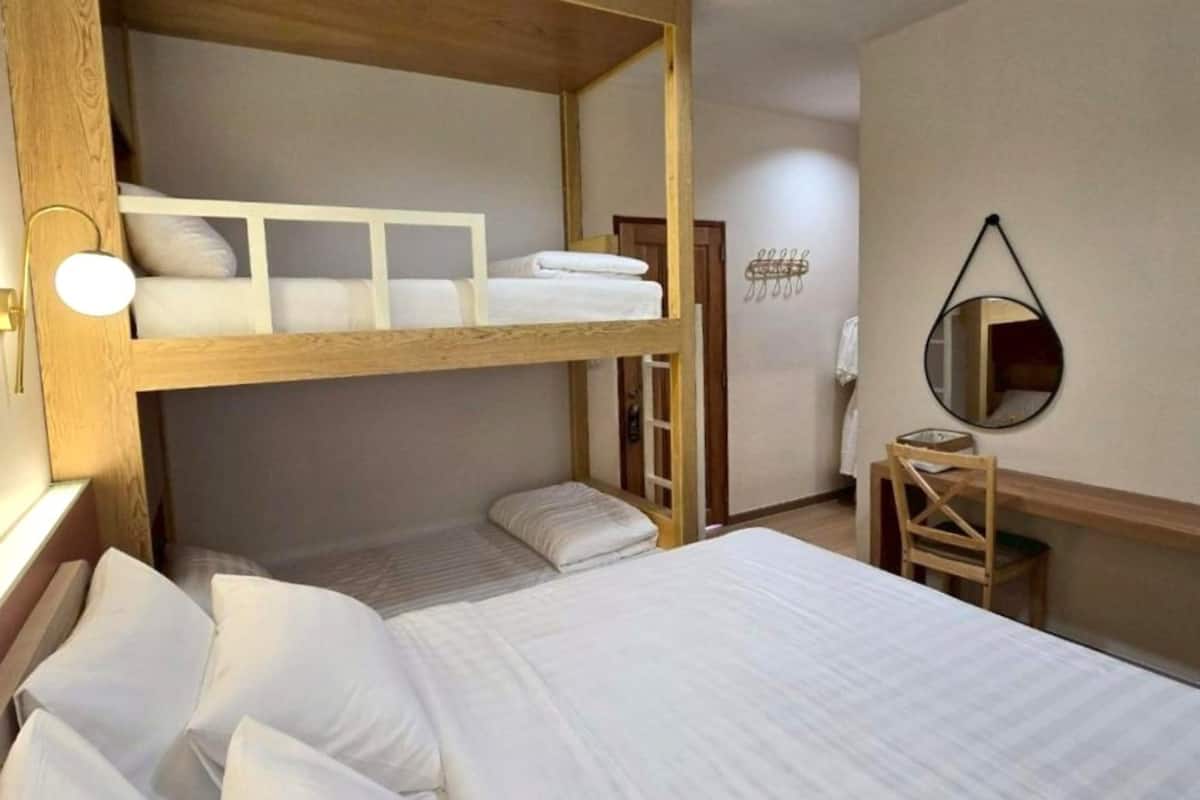 Quarto com beliche, escrivaninha, cadeira, espelho e toalheiro fixado na parede.