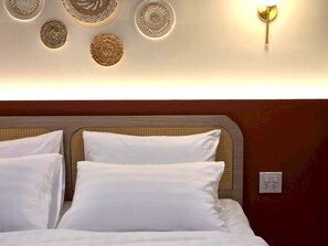 A bed with white bedding, a headboard with a woven pattern, and wall-mounted decorative plates. - Inn De Sea Poshtel (Bangkok)