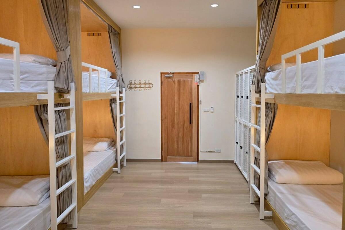 Quarto de hotel com beliches, porta de madeira e corredor.