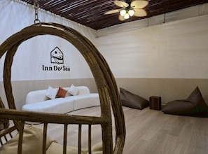 A room with a white sofa, a hanging chair, and a ceiling fan. - Inn De Sea Poshtel (Bangkok)
