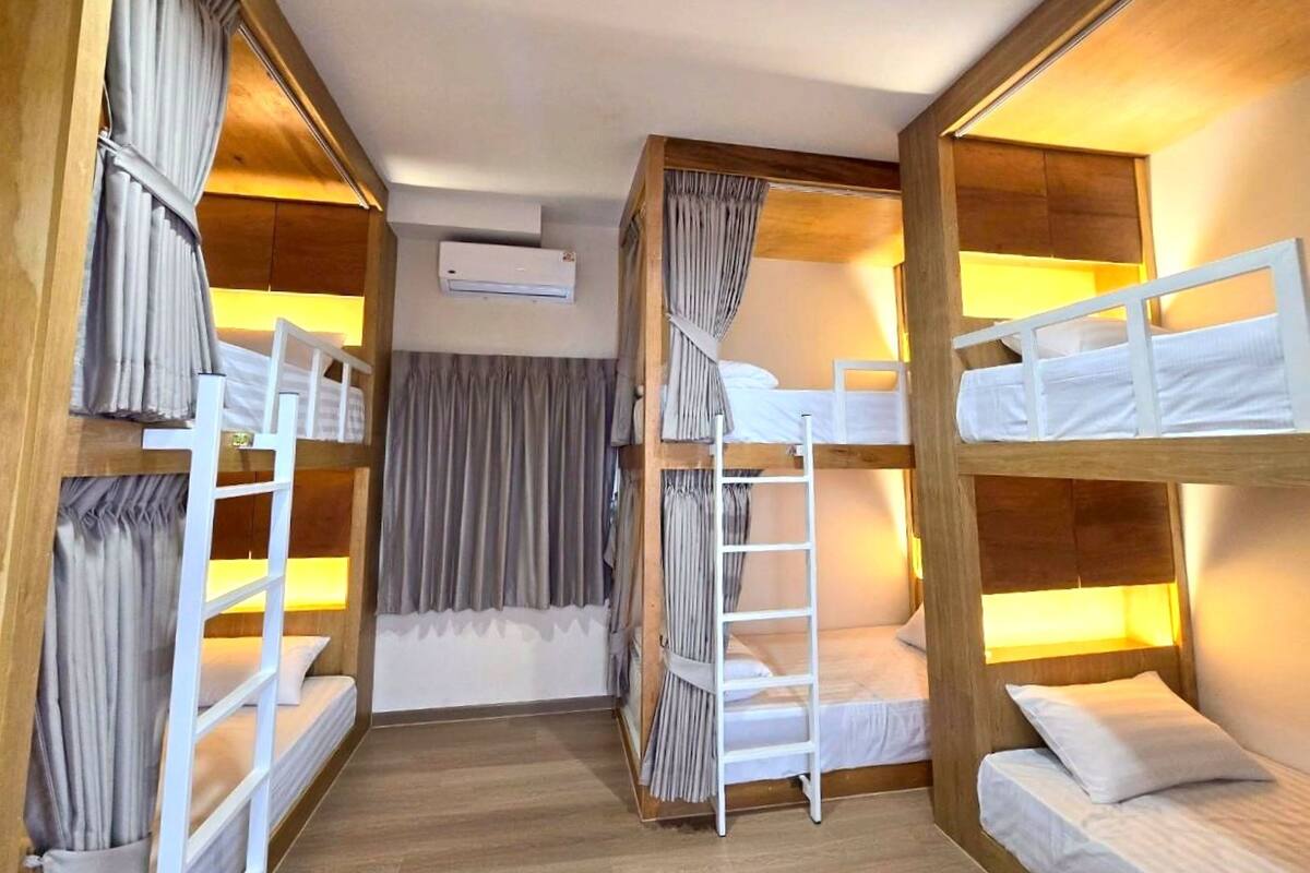 Quarto com beliches, paredes de madeira, escada e ar condicionado.