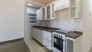 A compact kitchen with white cabinets, a gas stove, and a built-in oven.