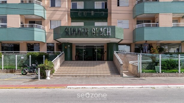A multi-story hotel with a prominent "Summer Beach" sign, outdoor seating, and a motorcycle parked outside.