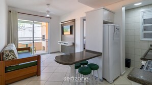 A modern kitchen with a built-in fridge, a small dining area, and a sofa with a view to the outside.