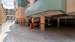 A multi-level parking garage with several cars parked, a red trash bin, and a clear sky.