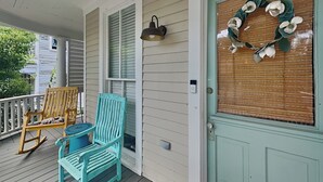 Une véranda avec un fauteuil à bascule, une chaise bleue et une table en bois.