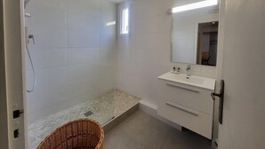 A bathroom with a shower, a sink, a mirror, and a wicker basket.
