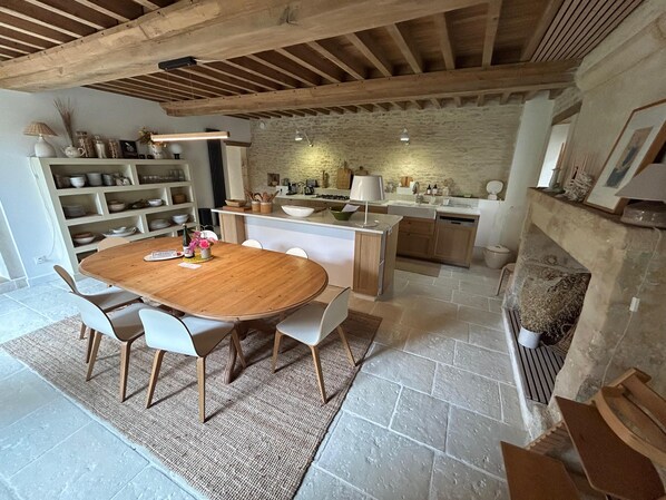 A spacious kitchen with a stone wall, wooden beams, and a large island.