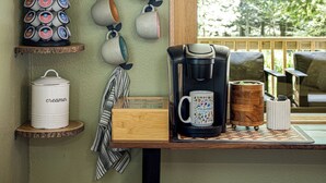 A kitchen area with a coffee maker, mugs, and a tea kettle on a wooden countertop. - Streamside | Nature-Lux w/ Hot Tub, Sauna, Firepit, Game Area, Beautiful Setting (Traverse City)