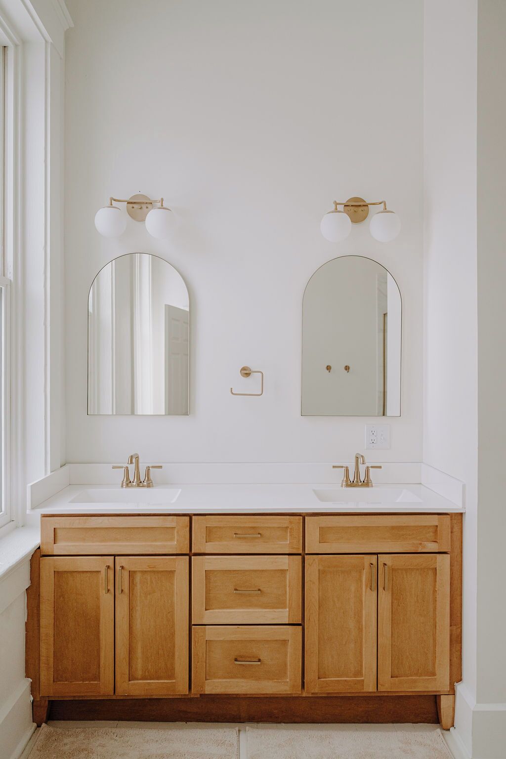 Un baño con dos lavamanos, armarios de madera y espejos montados en la pared.