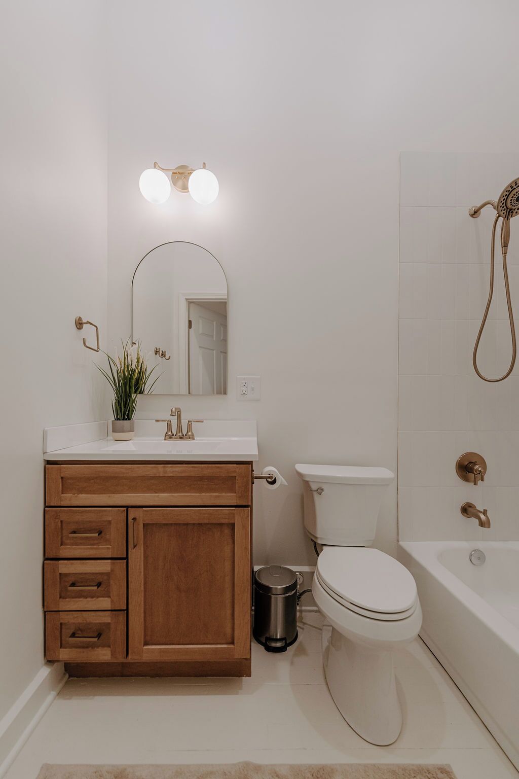 Un baño con tocador de madera, elementos blancos, inodoro, bañera y ducha.