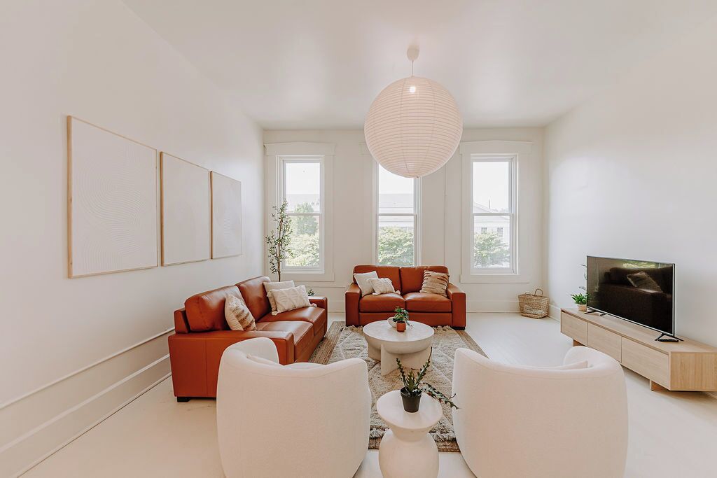 A modern living room with two red sofas, a white coffee table, and a TV on a wooden stand.