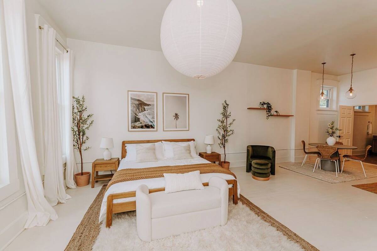 Un dormitorio amplio con una cama grande, mesitas de noche, un escritorio y una silla.
