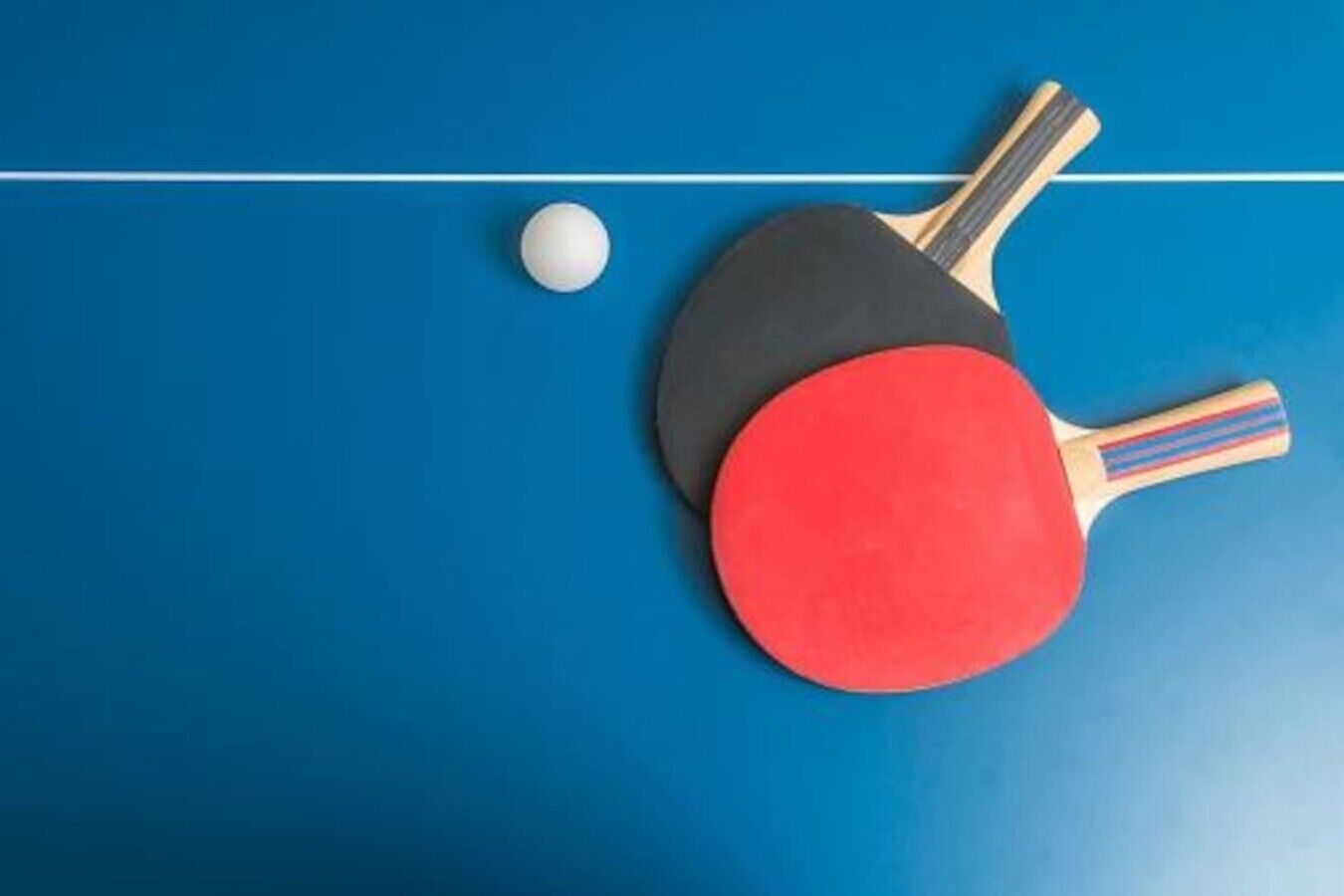 To batonger og en bordtennisbold på et blåt bord.