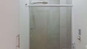 Un baño pequeño con ducha de vidrio, inodoro y lavamanos.