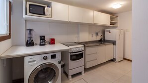 Cocina compacta equipada con microondas, cafetera, licuadora, lavadora, horno y refrigerador.