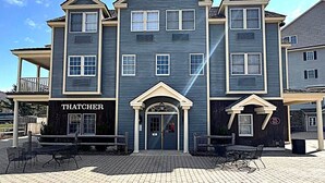 A two-story building with a dark blue exterior, a central entrance with a decorative arch, and a sign reading "THATCHER". - Luxury Jiminy Ski On Off Village Ctr Condo Sleeps4 (Hancock)