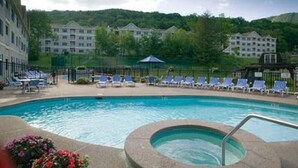 A swimming pool with lounge chairs and a hot tub, surrounded by buildings and greenery. - Luxury Jiminy Ski On Off Village Ctr Condo Sleeps4 (Hancock)