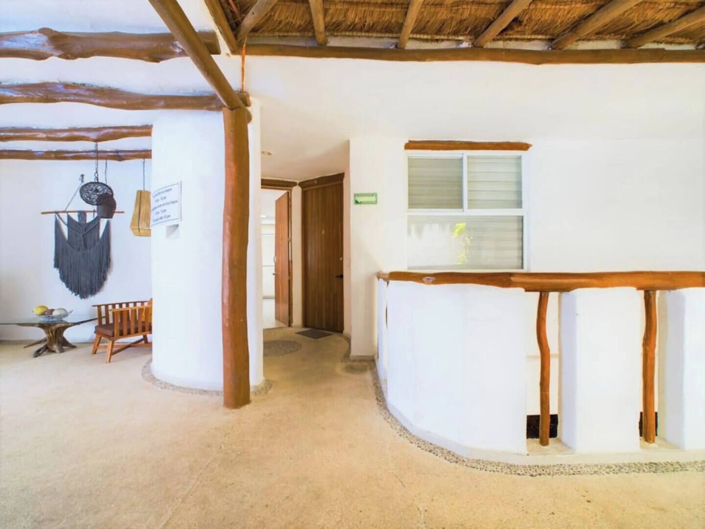 Een kamer met een houten plafond, een witte muur, een raam en een deur.
