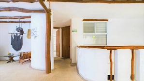 Ein Zimmer mit Holzbalkendecke, weißer Wand, Fenster und Tür.