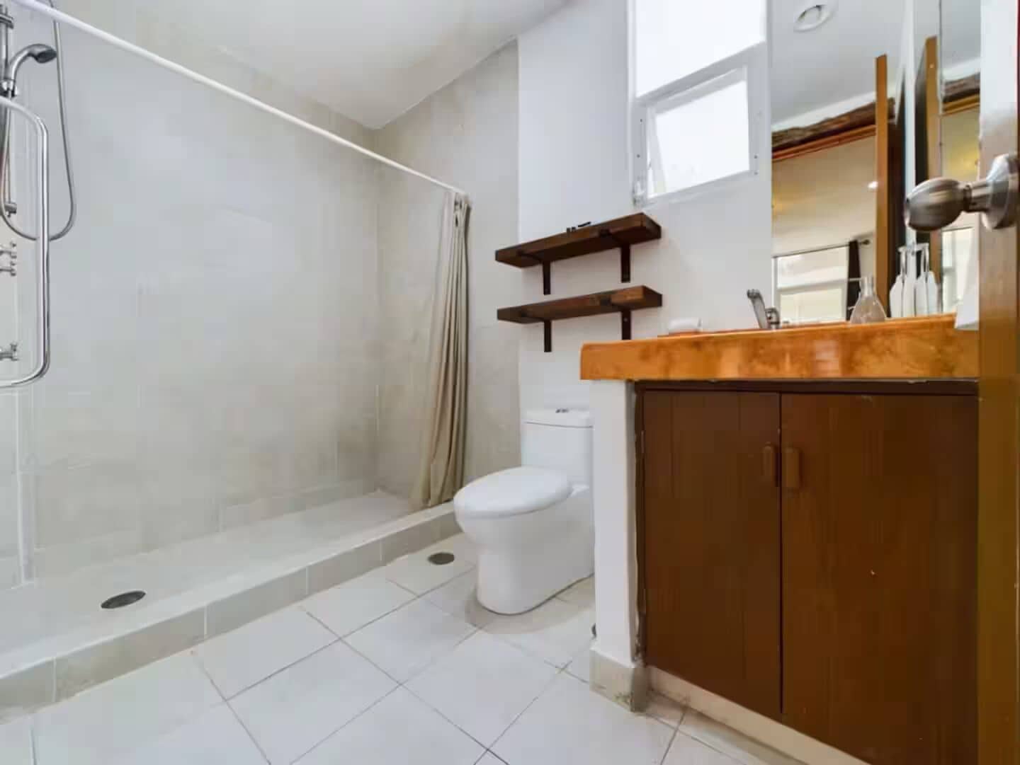 A bathroom with a shower, toilet, and wooden cabinets.