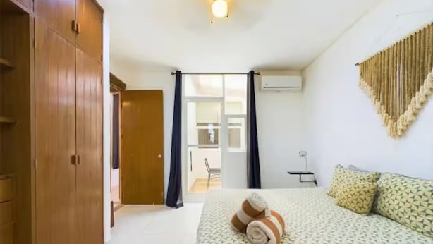 Ein Schlafzimmer mit Bett, Schrank, Schreibtisch und einem Fenster mit Vorhängen.