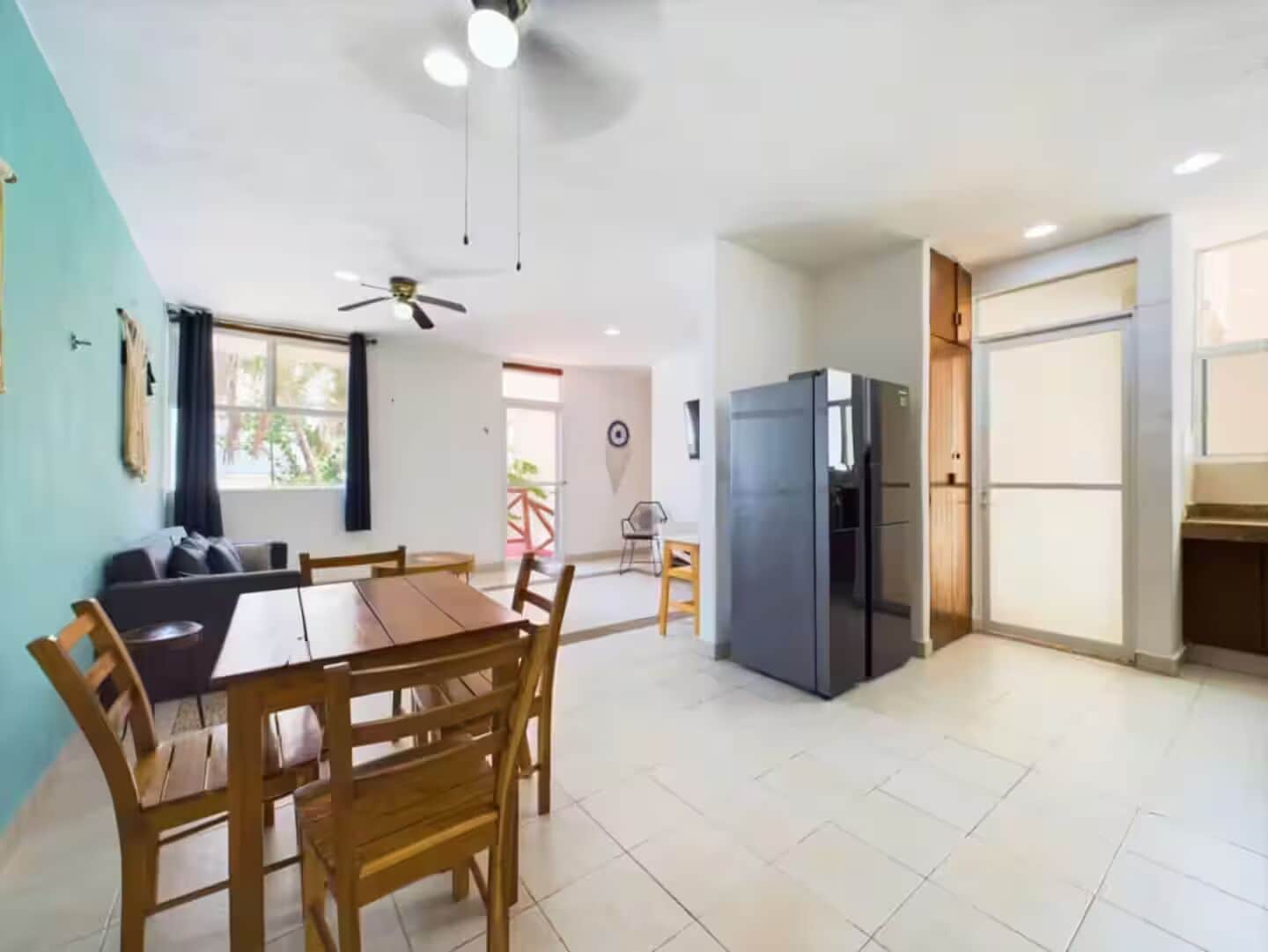 A modern kitchen with a refrigerator, wooden dining table, and chairs.