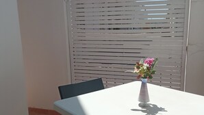 Une petite table blanche, ornée d’un vase de fleurs, entourée de chaises.