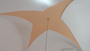 Un plafond orné d’un motif géométrique et d’une chaîne suspendue.