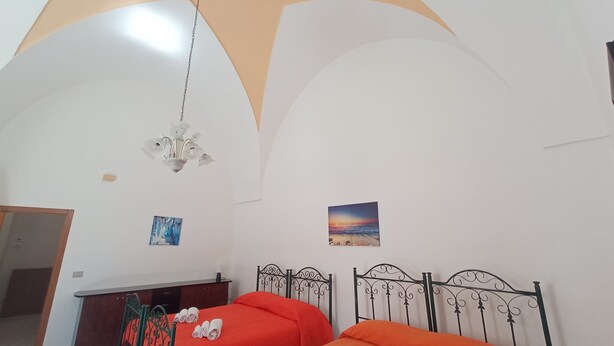 Une chambre avec deux lits, un lustre et deux tableaux accrochés au mur.