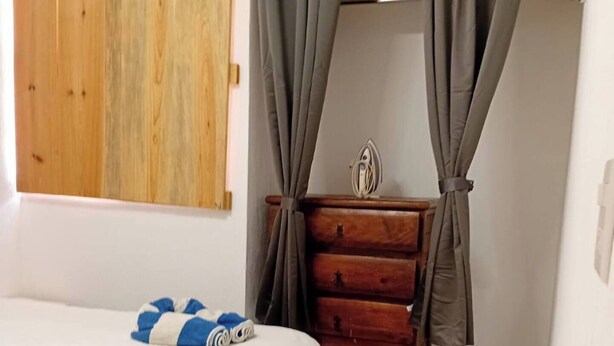 A bedroom with a bed, a wooden dresser, and curtains. - Aldea Tulum 1st floor (Aldea Tulum)