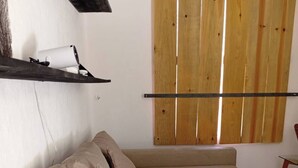 A modern living room with a beige sectional sofa, a wooden slat wall, and a small table with a chair. - Aldea Tulum 1st floor (Aldea Tulum)