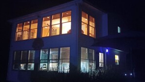 A two-story building with multiple windows, some of which are illuminated.