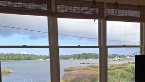 A room with a large window offering a view of a lake, dock, and surrounding greenery.