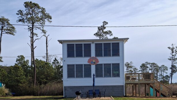 A two-story building with a beach view, outdoor seating, and a wooden deck.